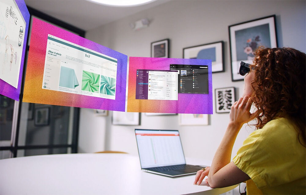 Okulary VITURE XR Luma Pro Czarny okulary założone na kobiecie korzystającej z nich przed nią wirtualne ekrany oraz laptop na białym stole wyświetlacze Sony micro-OLED przekątna rozdzielczość 4K szeroki kąt widzenia realistyczne treści