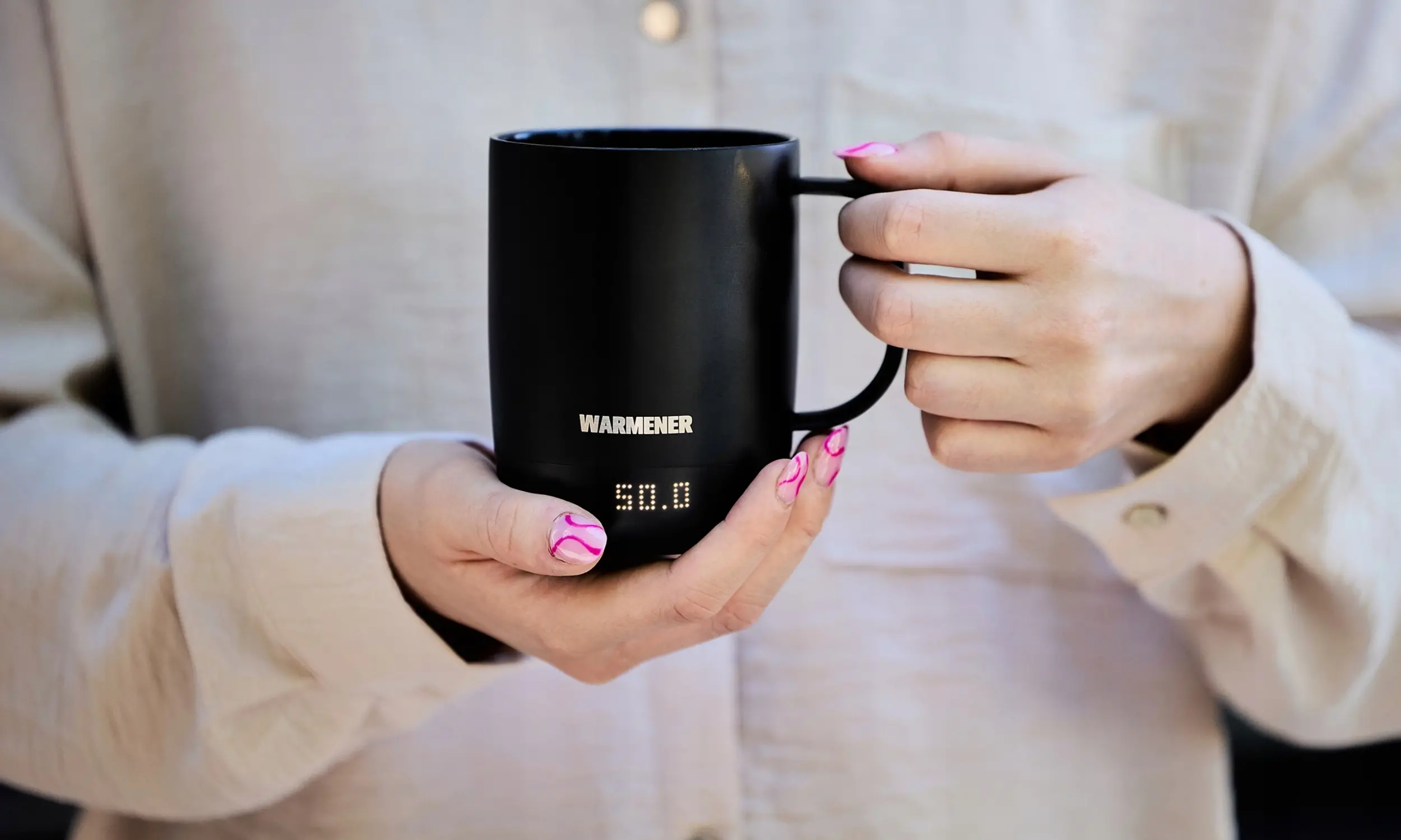 Podgrzewany kubek Warmener na biurku obok laptopa