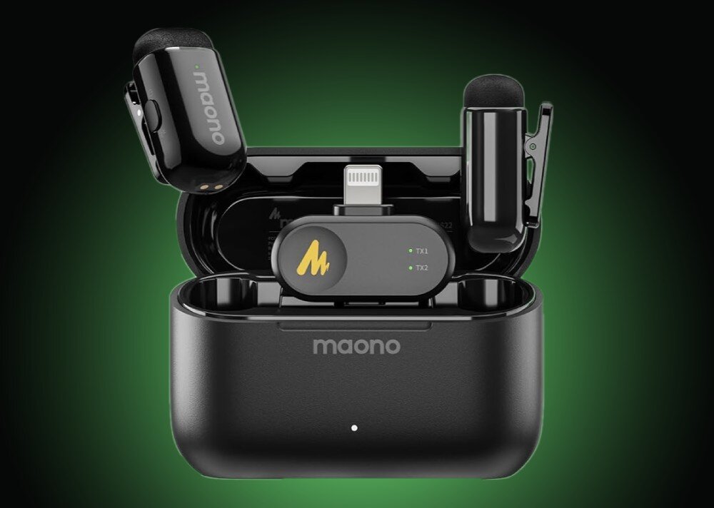 System bezprzewodowy MAONO WM622 PB2 czarny, błyszczący mikrofon o obłym kształcie umieszczony na czubku palca wskazującego, w tle widoczna jest graficzna wizualizacja fali dźwiękowej w kolorach białym i zielonym na czarnym tle