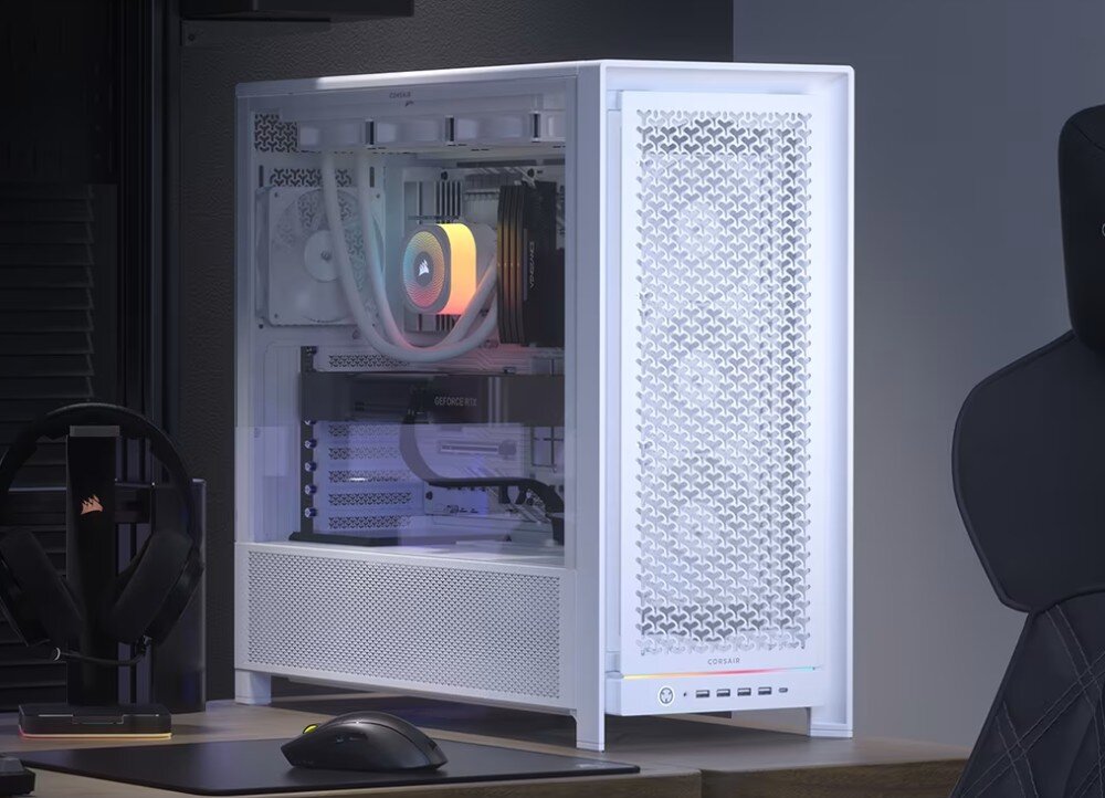 Obudowa CORSAIR Frame 5000D RS Komputer stacjonarny w obudowie z przeszklonym panelem bocznym, przez który widać podświetlone na kolorowo komponenty, umieszczony na biurku obok słuchawek i myszki