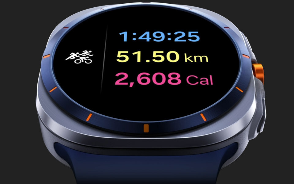 Nieco przechylony widok Galaxy Watch Ultra. Wybrano tryb oszczędzania energii. Funkcja śledzenia triathlonu jest na ekranie. Całkowity czas spędzony na ćwiczeniach wzrasta z 1 godziny 49 minut 23 sekund do 25 sekund. Dystans wynosi 51,50 kilometrów. Spalone kalorie wzrastają z 2604 kalorii do 2608 kalorii.