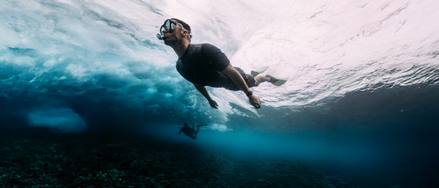 Mężczyzna w kostiumie kąpielowym pływa w oceanie z Galaxy Watch Ultra na nadgarstku.