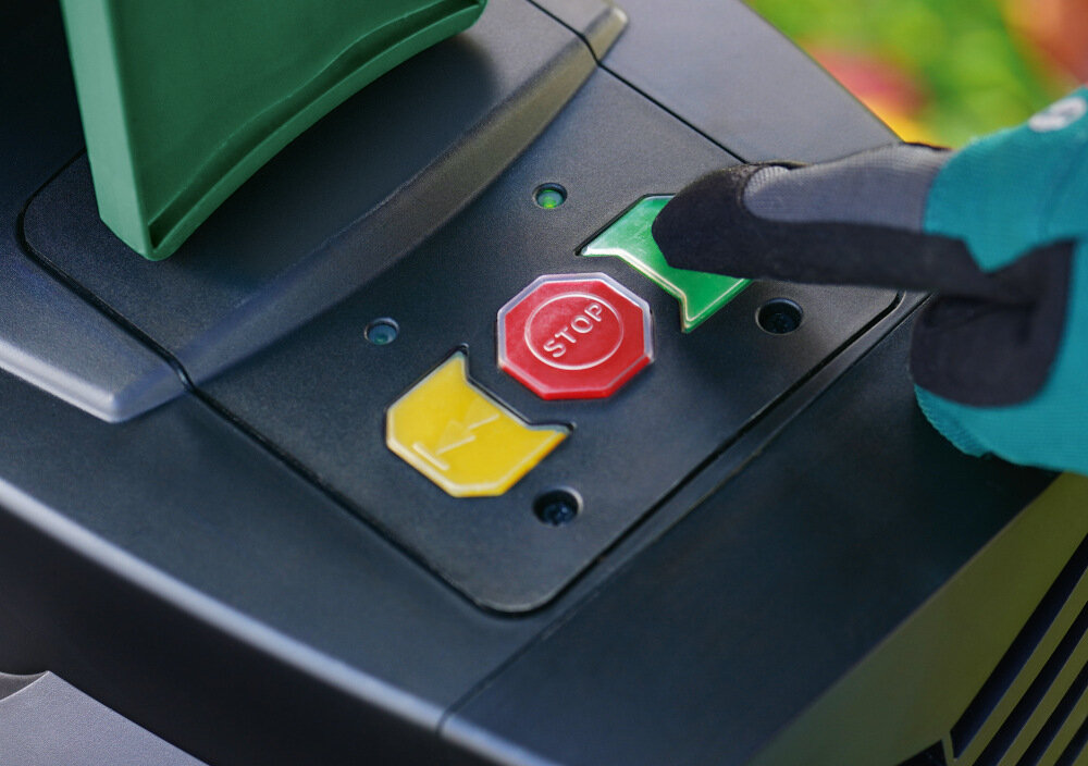 Rozdrabniacz do gałęzi BOSCH AXT 25 TC elektryczny 2500 W sekator + rękawice ogród zbliżenie na przyciski do uruchomienia maszyny przyciski żółty czerwony i zielony osoba przyciska zielony przycisk wydajny bezszczotkowy silnik indukcyjny o mocy 2500 W duża siła cięcia wysoka efektywność dłuższa żywotność mniejsza potrzeba serwisowania