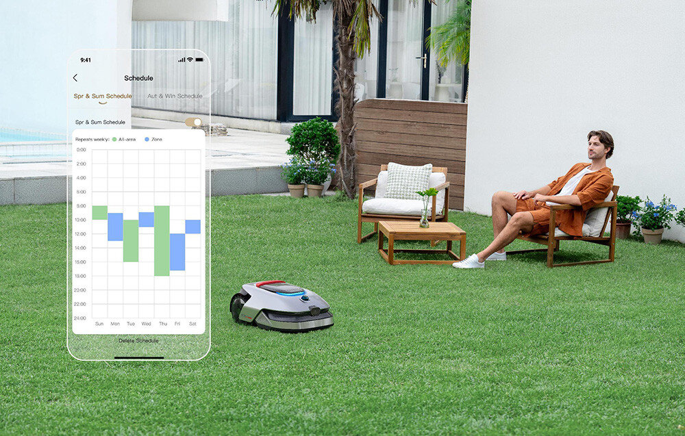 Robot koszący DREAME A2 robot stoi na trawie w tle osoba siedzi na fotelu ogrodowym dom aplikacja funkcja Dual-Map Management stworzenie dwóch niezależnych map koszenia własny harmonogram i granice dostosowanie pracy robota do potrzeb posesji