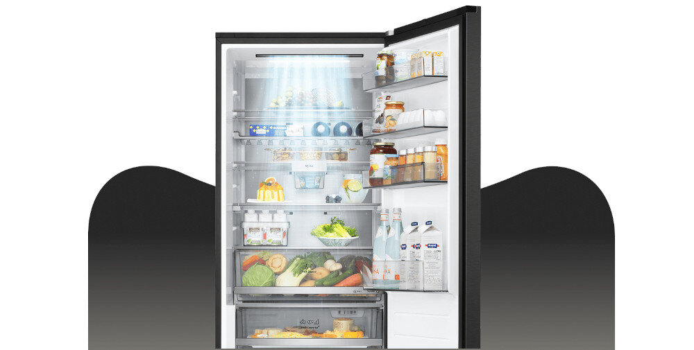LODÓWKA LG GBBS727AEV Grafika przedstawia otwartą lodówkę LG z górną chłodziarką, wypełnioną jedzeniem rozmieszczonym na półkach, w szufladach i na balkonikach drzwi. Jasne oświetlenie LED w górnej części komory równomiernie rozjaśnia wnętrze, eksponując świeże warzywa, owoce, napoje oraz produkty w opakowaniach kartonowych i słoikach DoorCooling+ LG szybkie chłodzenie równomierne chłodzenie chłodzenie drzwi świeżość żywności chłodne napoje technologia LG lepsza cyrkulacja powietrza dłuższa świeżość