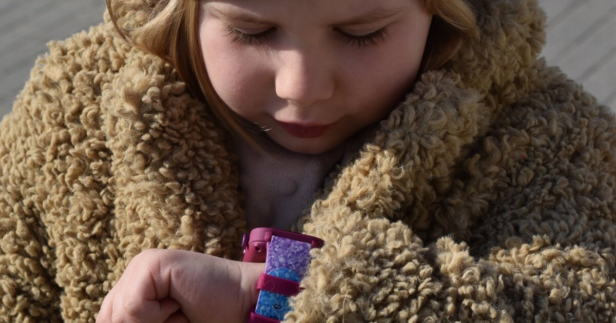 Smartwatch KIDIZ Chat 2.1  Dziecko używa smartwatcha KiDiZ Watch z czarnym paskiem, bawiąc się aparatem na zegarku. 