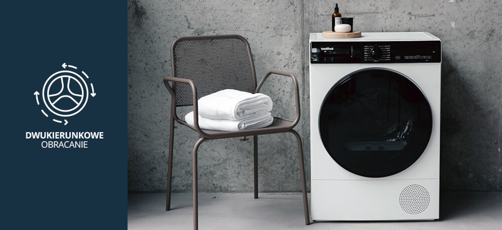 Suszarka VESTFROST VT-FW4EHY70EU Na zdjęciu znajduje się suszarka Vestfrost o ciemnym froncie, ustawiona we wnętrzu z betonu i czarną zabudową. Po lewej stronie widnieje grafika wskazująca na funkcję dwukierunkowego obracania bębna, która pozwala równomiernie i skutecznie suszyć odzież dwukierunkowe obracanie bębna równomierne suszenie brak zbijania się ubrań przeciw skręcaniu ubrań równy efekt suszenie bez wilgotnych miejsc