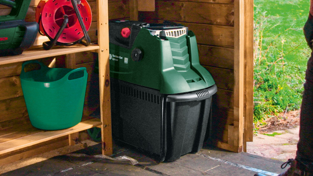 Rozdrabniacz do gałęzi BOSCH AXT 25 TC elektryczny 2500 W sekator + rękawice garaż szopa drewniana konstrukcja rozdrabniacz ustawiony pod ścianą obok półka z narzędziami możliwość demontażu leja wysokość rozdrabniarki podczas przechowywania wynosi zaledwie 67 cm funkcja składania oszczędza miejsce wygodne przechowywanie