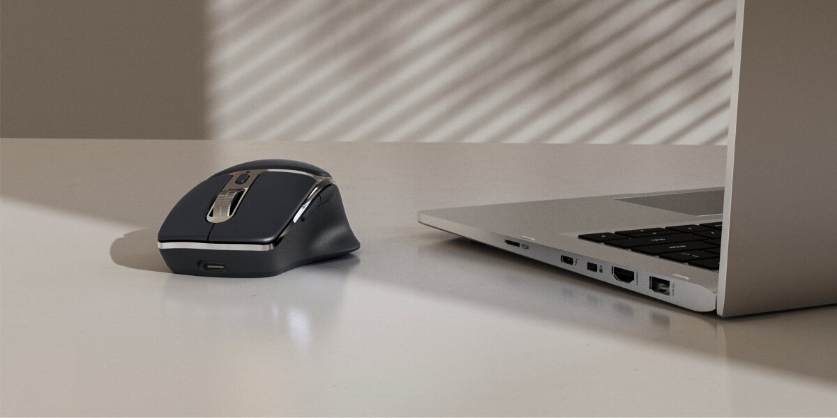 Mysz HAMA WM-800 Czarny Czarna bezprzewodowa mysz komputerowa o ergonomicznym kształcie leży na jasnym biurku obok otwartego laptopa. Widoczny port ładowania USB-C na przedzie myszki w minimalistycznym biurze.