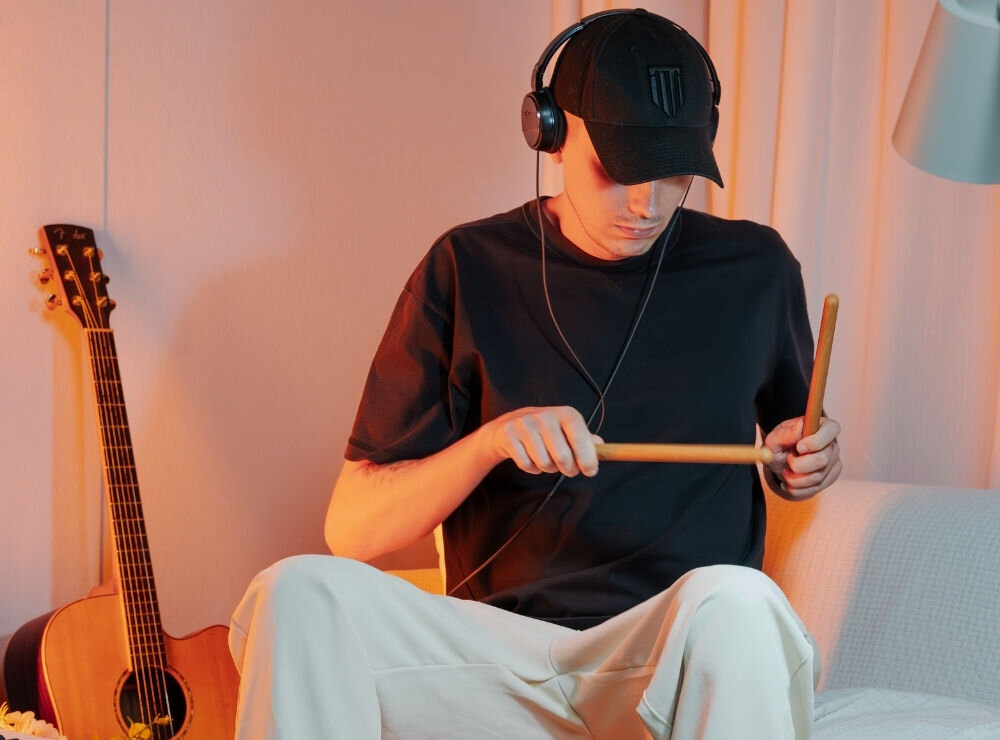  Przenośna perkusja elektroniczna AeroBand PocketDrum 2 Max – mobilność i wygoda, osoba z założonymi słuchawkami nausznymi oraz pałeczkami od perkusji