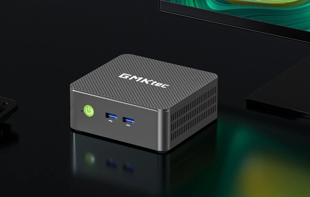 Komputer GMKTEC G3S Urządzenie o fakturze karbonu z napisem na górnej pokrywie i podświetlonym zielonym przyciskiem zasilania umieszczone na czarnym blacie