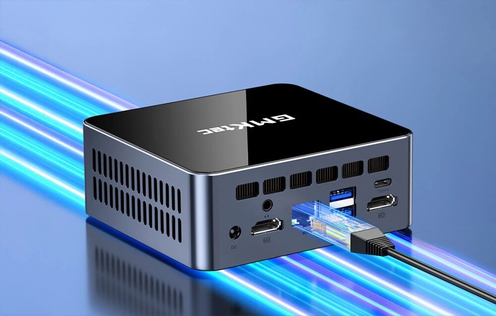 Komputer GMKtec M2 Pro S Mały komputer o ciemnej obudowie z błyszczącą górną powierzchnią, do którego z tyłu podłączony jest kabel sieciowy i widoczne są liczne porty