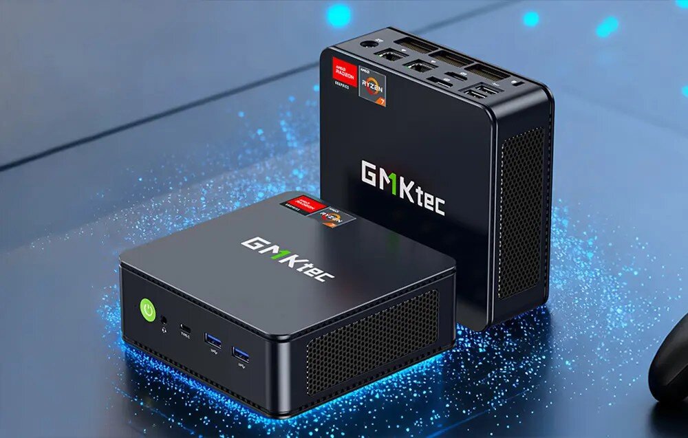 Komputer GMKTEC M5 Ultra Dwa małe, ciemne komputery z zielonym przyciskiem zasilania i logiem, z których jeden stoi pionowo, a drugi leży na płaskiej powierzchni emitującej niebieskie światło