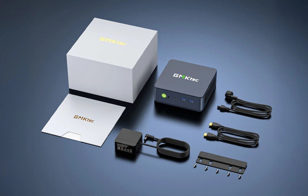 Komputer GMKTEC M5 Ultra Zestaw elementów na ciemnoniebieskim tle zawierający mały komputer z zielonym przyciskiem, białe pudełko, zasilacz, kable HDMI i zasilający oraz uchwyt ze śrubkami