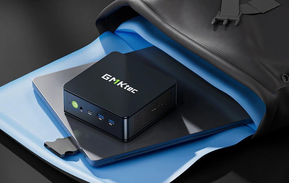 Komputer GMKTEC M6 Ultra Czarny mini komputer z widocznym przyciskiem zasilania i dwoma portami USB na niebieskim tle z efektem ruchu