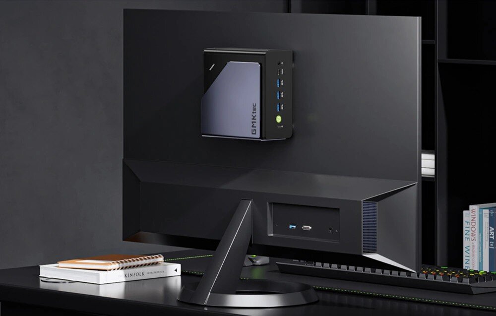 Komputer GMKTEC NucBox K12 Mini komputer przymocowany do tylnej obudowy monitora za pomocą uchwytu montażowego w minimalistycznym otoczeniu biurowym