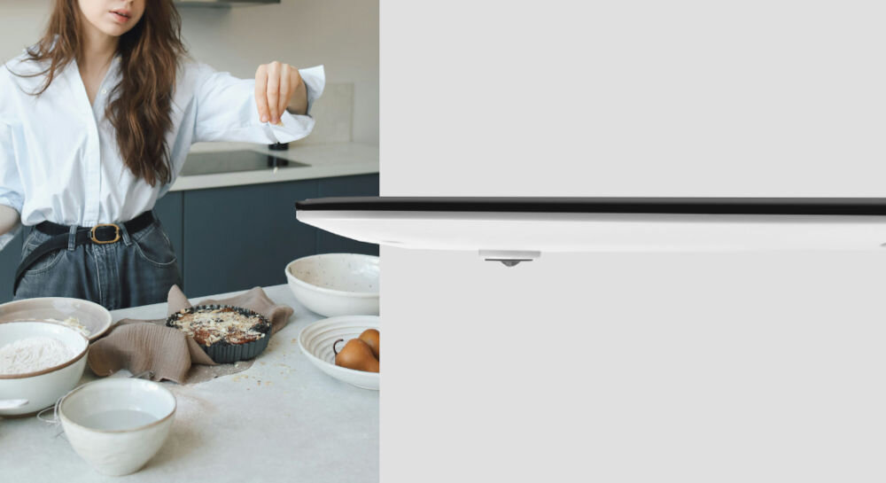 Waga kuchenna ETA Lori 277790050 Czarny  biały spód wagi nóżki szare tło kobieta posypuje potrawę ważenie w różnych jednostkach gramy kilogramy funty uncje objętość mleka i wody dokładność co 1 gram precyzyjne odmierzanie składników funkcja TARE usprawnienie codziennej kuchennej pracy