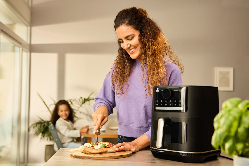 Air Fryer Frytkownica beztłuszczowa BRAUN MultiFry 5 HF5073 frytkownica czarna obudowa kobieta kroi pizzę na desce z 20 automatycznymi programami gotowania stylowy minimalizm funkcjonalność kompaktowy rozmiar 27 x 33,5 x 28 cm duża pojemność 6 litrów 1,6 kg frytek kurczak o wadze 1,5 kg oszczędność czasu i miejsca na blacie wygoda wszechstronność optymalne rezultaty przy minimalnym wysiłku 