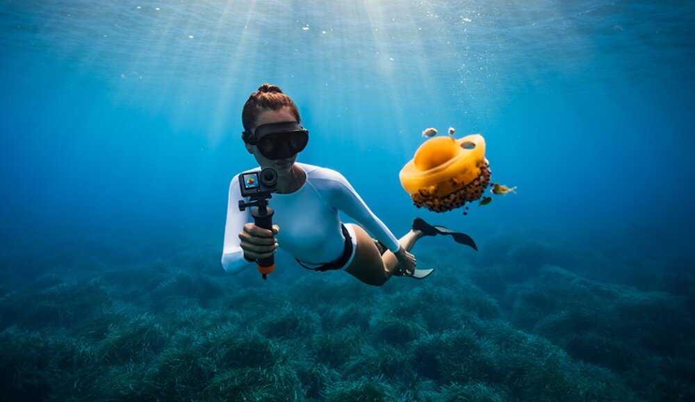 Kamera sportowa DJI Osmo Action 6 Nurek pod wodą trzymający kamerę na uchwycie obok pomarańczowej meduzy, wodoodporność, obudowa, ekosystem