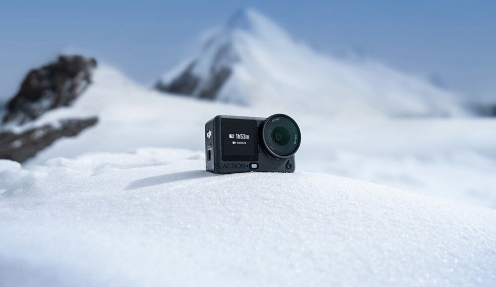 Kamera sportowa DJI Osmo Action 6 Kamera sportowa leżąca na ośnieżonej powierzchni z górami w tle, wytrzymałość, temperatura, bateria, czas działania, pamięć