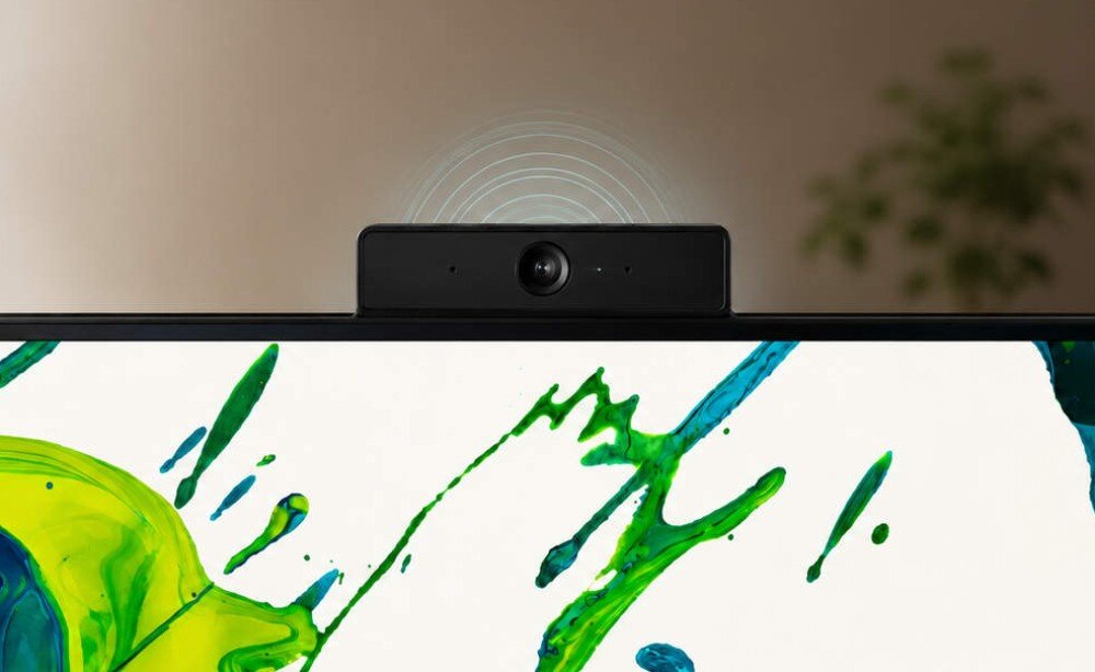 Komputer All in One ACER Aspire C24-2YE13U5UNL Zbliżenie na czarną kamerę internetową z obiektywem umieszczoną nad górną ramką ekranu, nad urządzeniem narysowano jasne łuki symbolizujące fale dźwiękowe lub sygnał, kamera, audio