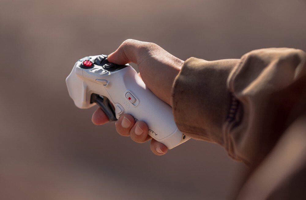 Dron ANTIGRAVITY A1 Dłoń trzymająca biały kontroler ruchu z przyciskami sterującymi, latanie, tryby, tryb FPV