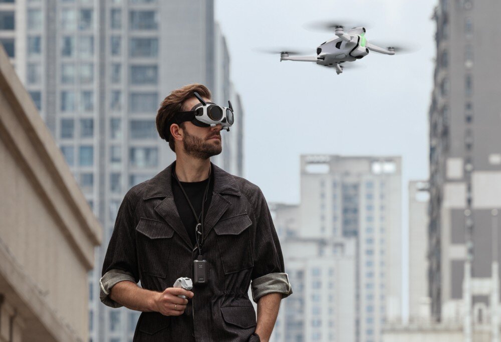 Dron ANTIGRAVITY A1 Mężczyzna w goglach i z kontrolerem ruchu na tle nowoczesnych budynków, aplikacja, edycja AI, dedykowany symulator