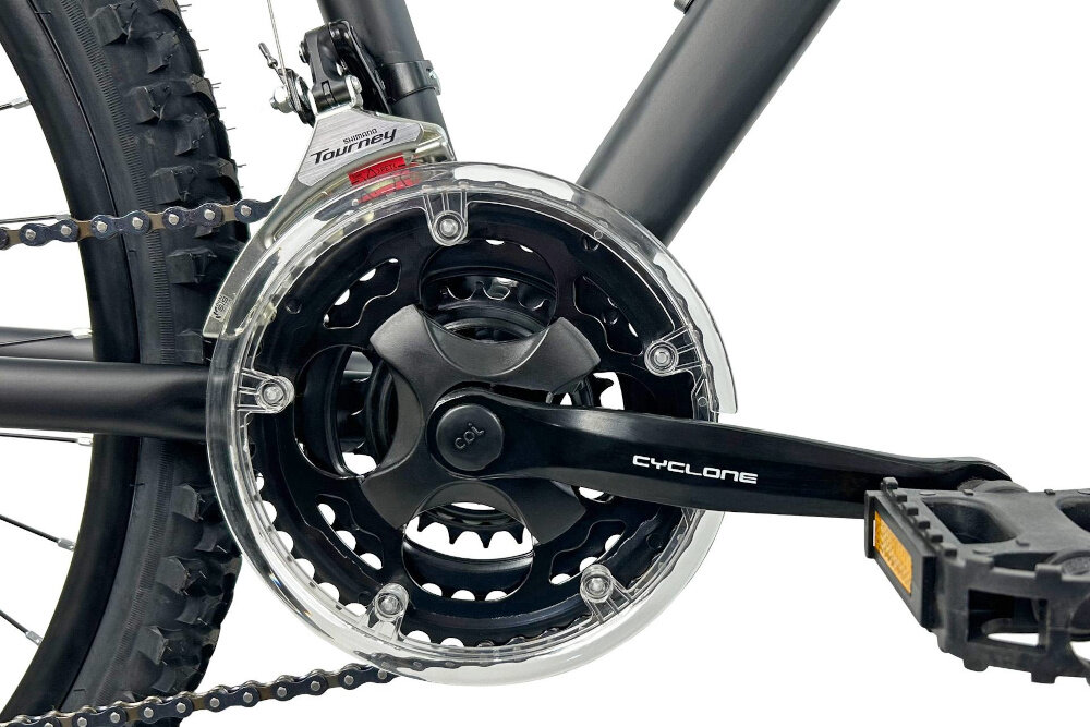 Zbliżenie na mechanizm korbowy roweru z widocznym napisem \'CYCLONE\' na ramieniu korby. Obok znajduje się przerzutka z napisem \'Shimano Tourney\'.