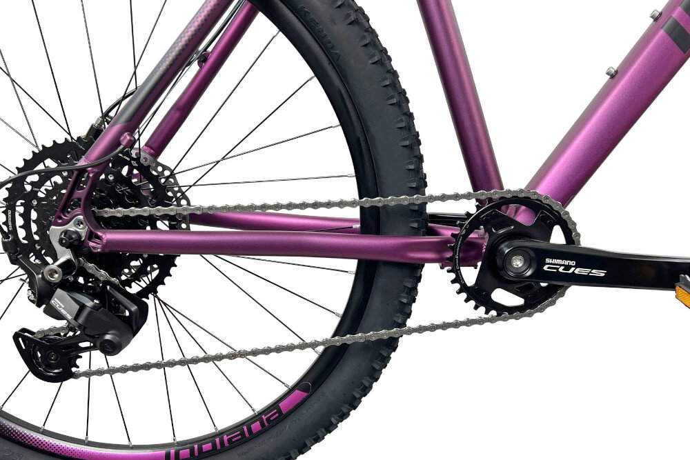 Rower górski MTB INDIANA X-Pulser 3.7 D17 27.5 cala damski Fioletowy zbliżenie na łańcuch i napęd białe tło łańcuch KMC Eglide 9V Cues dopasowany do napędów 9-rzędowych odpowiednia konstrukcja ogniw wspiera płynną współpracę z elementami układu napędowego zmiana przełożeń może odbywać się sprawnie i z zachowaniem odpowiedniej kultury pracy