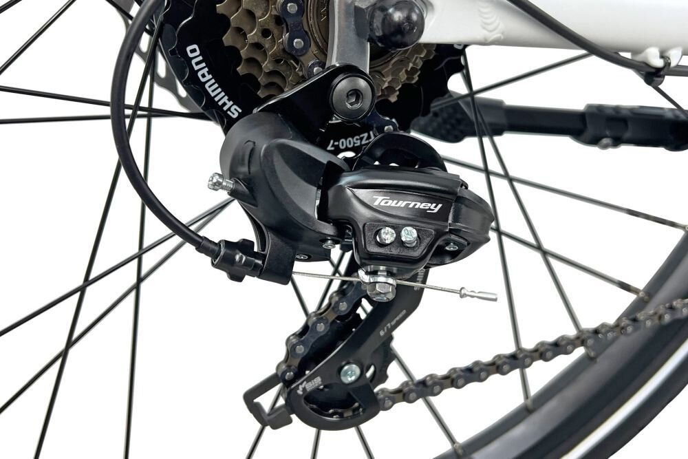 Zbliżenie na mechanizm przerzutki rowerowej z widocznymi napisami \'Shimano\' i \'Tourney\'. Elementy są zamontowane na ramie roweru.