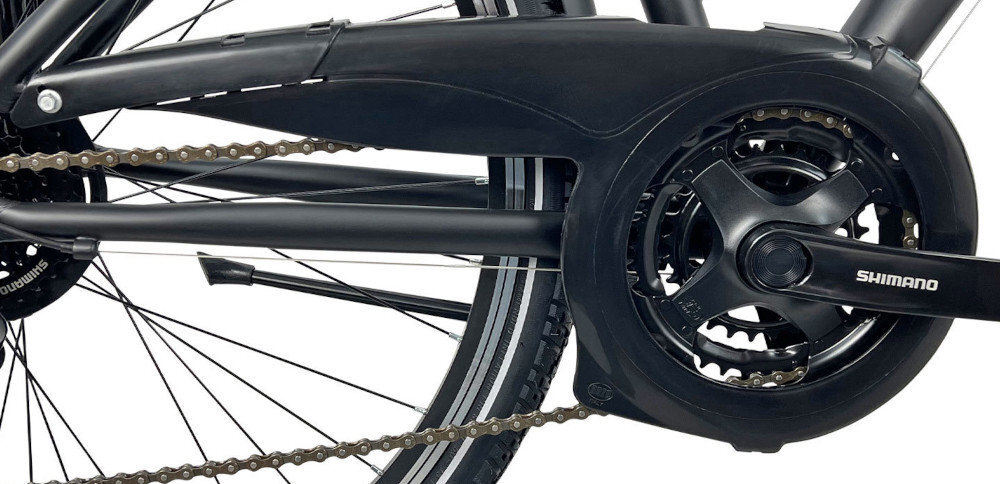 Zdjęcie przedstawia mechanizm napędowy roweru z widoczną osłoną łańcucha i zębatką. Na zębatce znajduje się napis \'SHIMANO\'.