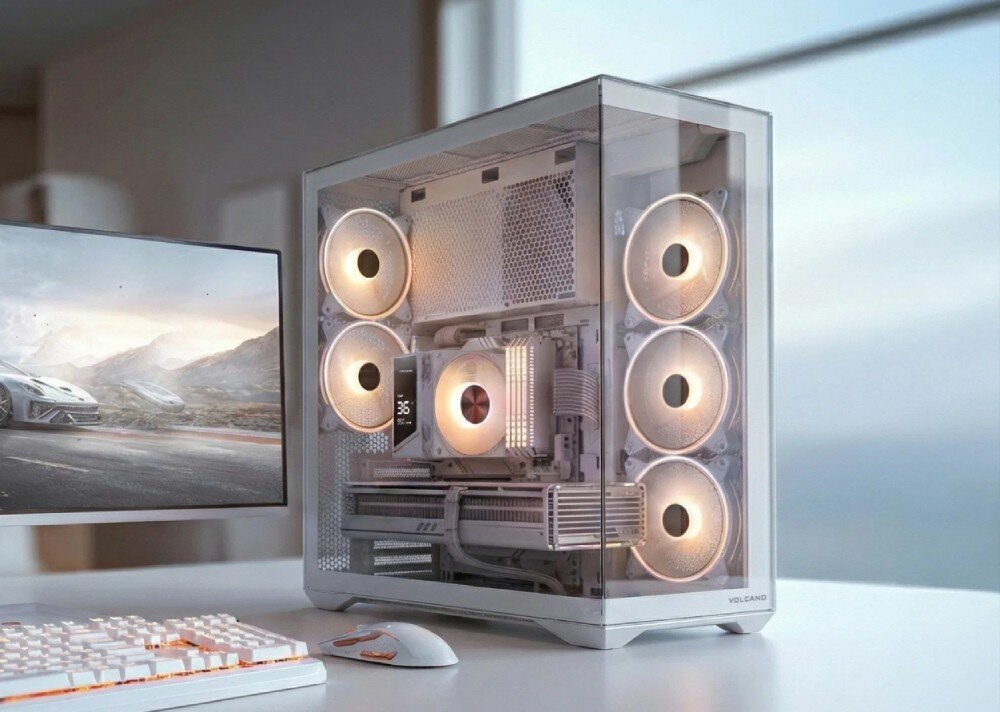 Obudowa MODECOM Volcano Space XL Full Tower NF Komputer stacjonarny w obudowie z przeszklonym frontem i bokiem stoi na biurku obok monitora. Wewnątrz widać podświetlone na różowo i niebiesko wentylatory, chłodzenie procesora z wyświetlaczem temperatury 36 stopni oraz kartę graficzną