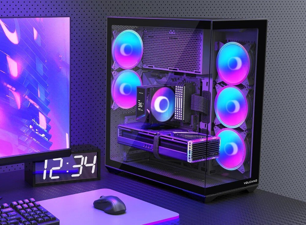 Obudowa MODECOM Volcano Space XL Full Tower NF Komputer stacjonarny w czarnej obudowie z przeszklonym frontem i bokiem stoi na biurku obok monitora. Wewnątrz widać podświetlone na różowo i niebiesko wentylatory, chłodzenie procesora z wyświetlaczem temperatury 36 stopni oraz kartę graficzną