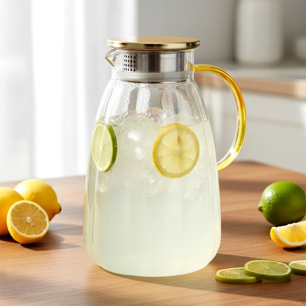 Szklany dzbanek z pokrywką wypełniony napojem z plasterkami cytryny i limonki oraz kostkami lodu. Obok dzbanka leżą całe i pokrojone cytryny oraz limonki na drewnianym blacie.