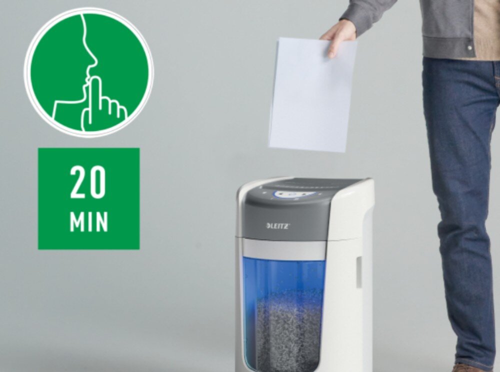 Niszczarka LEITZ IQ OptiMax Home Office 225 P5 Półzbliżenie na białą niszczarkę z niebieskim zbiornikiem wypełnionym pociętym papierem, i męską ręką wkładającą papier do niszczarki, obok zielonego koła z uciszonym znakiem i zielonego prostokąta z napisem '20 MIN