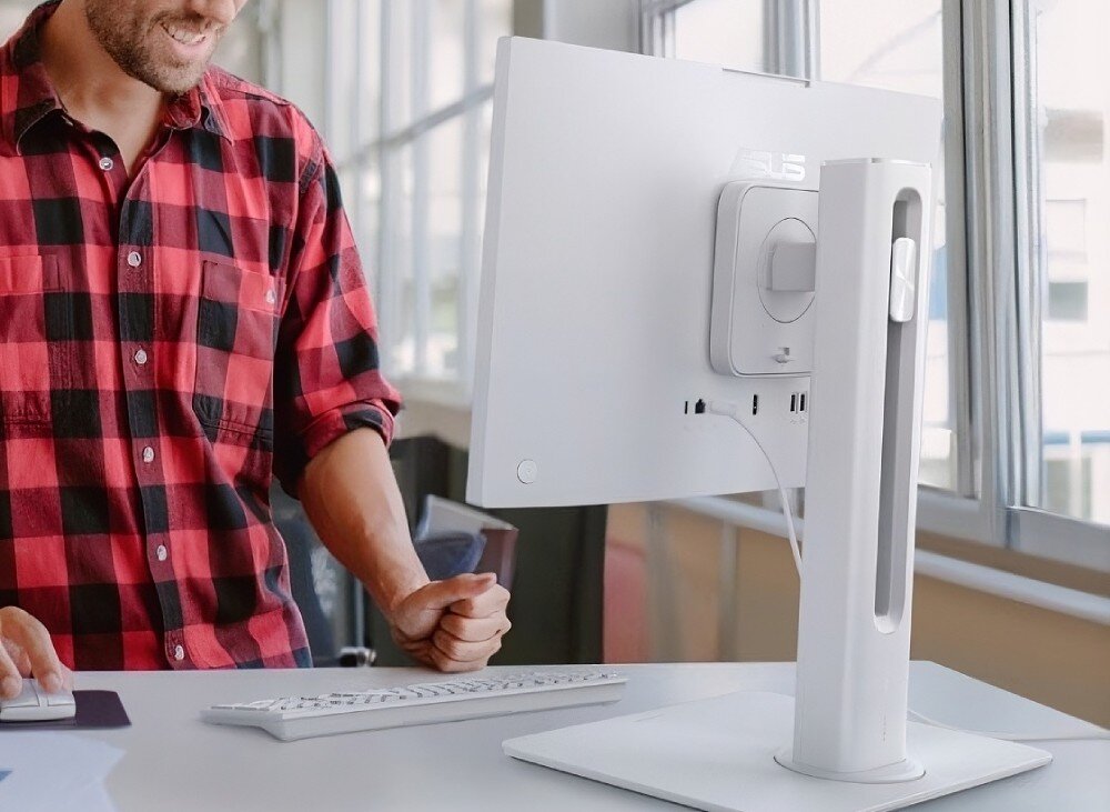 Komputer All in One ASUS ExpertCenter P440VAK-WPC204X komputer zamontowany na niebieskiej ścianie nad drewnianym biurkiem, wyświetlający zimowy krajobraz z ośnieżoną drogą, z widoczną na blacie klawiaturą oraz myszką, konstrukcja, zarządzanie kablami, zgodność z VESA