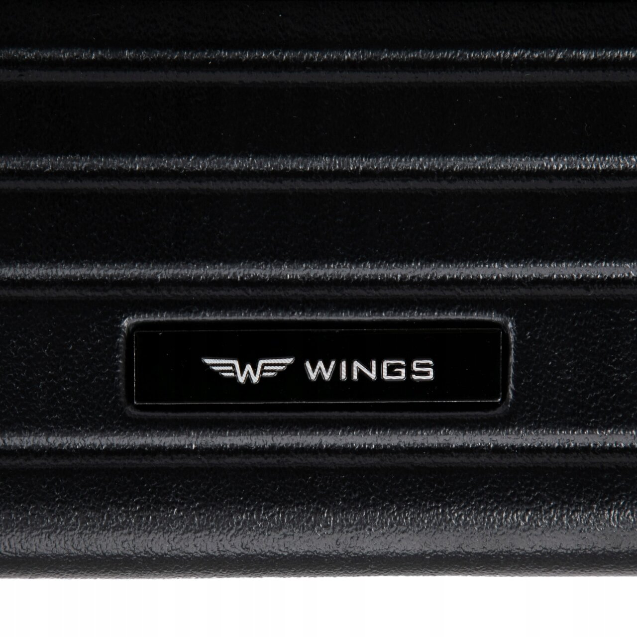 Czarna powierzchnia walizki z widocznym logo \'WINGS\' w kolorze białym na czarnym tle.