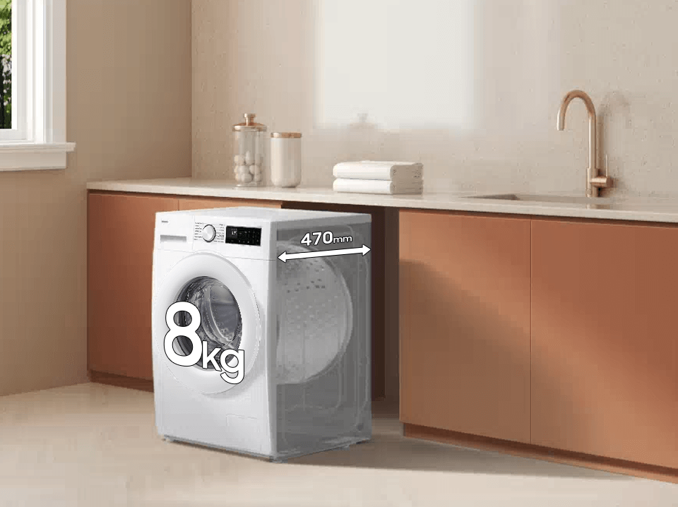 Pralka o pojemności 8 kg z oznaczeniem 470 mm, umieszczona w kuchni z brązowymi szafkami i złotym kranem. Na blacie znajdują się ręczniki i pojemniki.