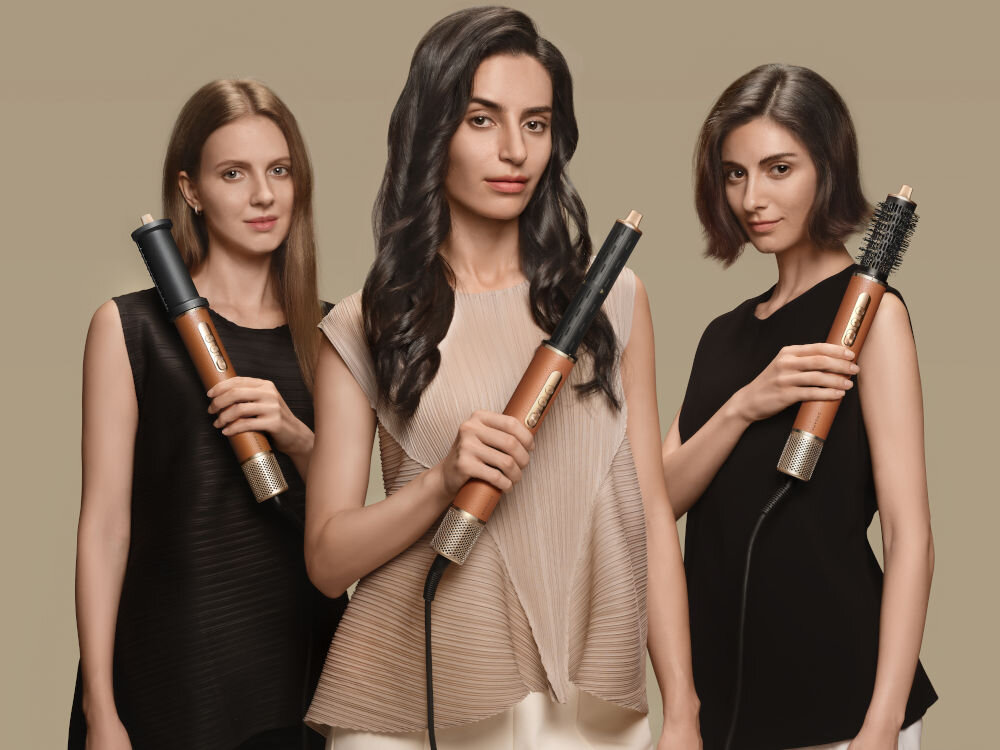 Suszarko-lokówka DREAME Air Styler Pro Złoty 1300W trzy modelki trzymające w dłoniach urządzenie z różnymi nałożonymi końcówkami do stylizacji