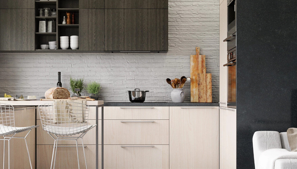 Nowoczesna kuchnia z jasnymi szafkami i ciemnym blatem, na którym stoi garnek i miska z przyborami kuchennymi. W tle widoczna jest ściana z białej cegły oraz otwarte półki z naczyniami.