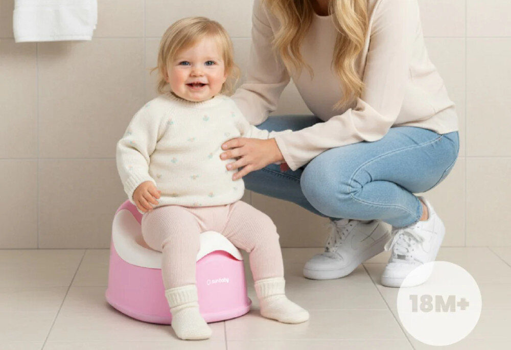 Dziecko siedzi na różowo-białym nocniku, obok klęczy osoba dorosła. Na nocniku widoczne jest logo \'SUN BABY\', a w rogu obrazka znajduje się napis \'18M+\'.