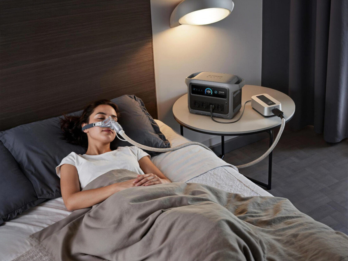Stacja zasilania ANKER Solix C1000 Gen 2, aplikacja, WiFi, TOU, limity, kobieta z podłączonym do niej inhalatorem, obok stacja zasilania na stoliku nocnym