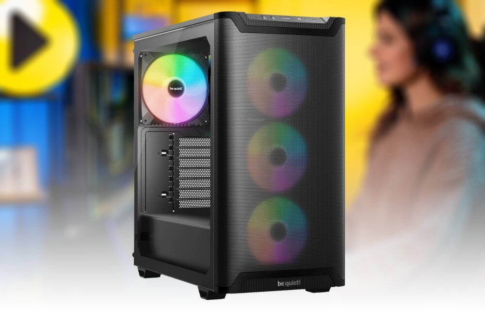 Komputer MAD DOG GeForce RTX5060Ti DLSS 4 Reflex Edition 2 BQ501LX-A01WR64WP Czarna obudowa komputera z przeszklonym panelem bocznym i siatkowym frontem, przez które przebija wielokolorowe światło trzech wentylatorów, na tle rozmytej sylwetki osoby