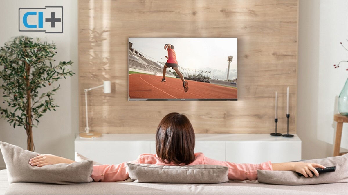 Telewizor SHARP 32HA1705E - Proste podłączenie modułu CI+, kobieta oglądająca sprot na telewizorze, siedząca w salonie na kanapie