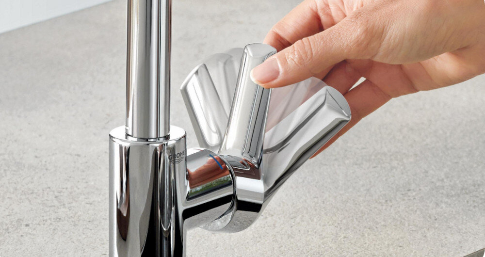 Zlewozmywak jednokomorowy z ociekaczem GROHE K200 31562SD1 Stal szlachetna 50x86 + bateria stojąca Bau Edge 31367001 Na zdjęciu w zbliżeniu widać chromowaną baterię kuchenną GROHE, której dźwignia regulacyjna jest płynnie odchylana dłonią. Rozmyte kontury uchwytu w kilku pozycjach podkreślają lekkość sterowania strumieniem i temperaturą wody GROHE SilkMove ceramiczna głowica precyzyjna regulacja strumienia wody niezawodność trwałość komfort użytkowania 20 lat bezawaryjność codzienna wygoda