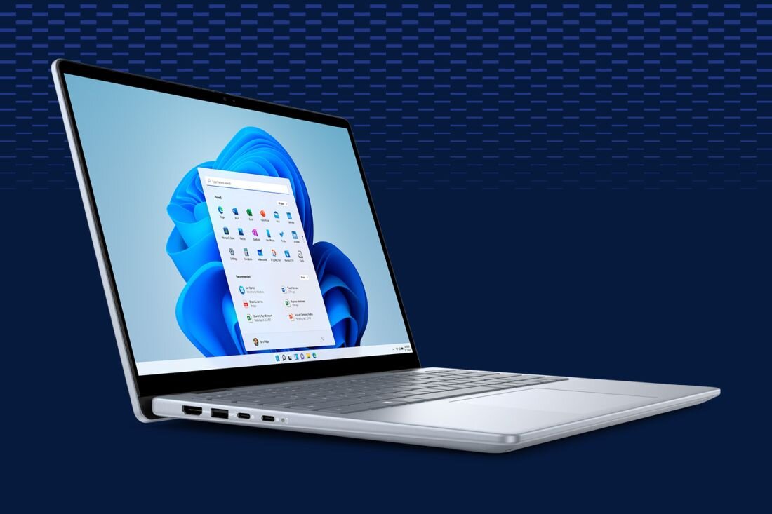 Laptop z otwartym ekranem, na którym widoczny jest interfejs systemu Windows 11. Urządzenie ma srebrną obudowę i kilka portów po boku.