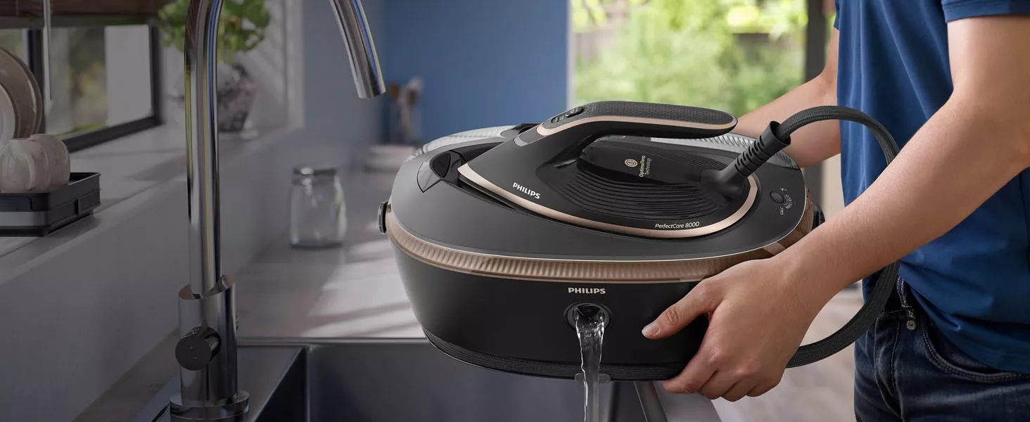 Osoba trzyma generator pary marki PHILIPS, z którego wylewa się woda do zlewu. Na urządzeniu widoczne są napisy: \'PHILIPS\' i \'PerfectCare 8000\'.