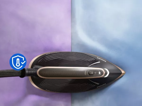 Zdjęcie przedstawia żelazko parowe na dwukolorowym tle, z widocznym logo producenta i ikoną temperatury. Żelazko ma ciemną stopę z jasnymi elementami i przyciskiem na uchwycie.