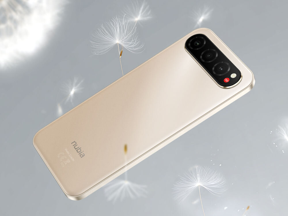 Smartfon NUBIA Air 8/256GB 6.78 120Hz Smartfon nubia w kolorze złoto-beżowym (sand gold) leży tyłem na jasnym tle. W tle widać puszyste nasiona dmuchawca. Widoczny jest podłużny, potrójny moduł aparatu z czerwonym akcentem.
