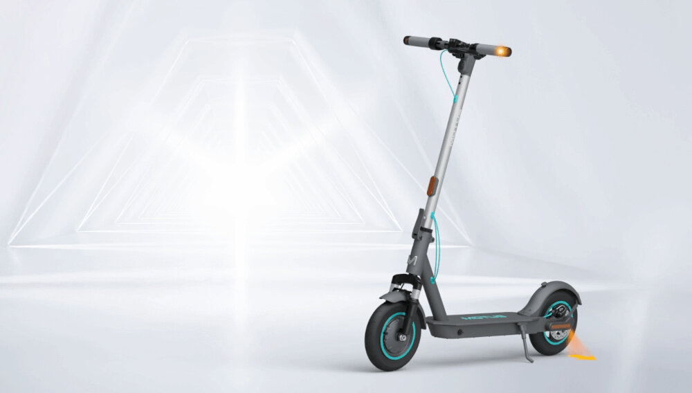 Hulajnoga elektryczna MOTUS Scooty 10 Plus Gen 6 65km 500W Amortyzacja 10 cali Szary hulajnoga widoczna z boku zdjęcie na szaro-białym tle do jazdy po mieście dynamiczne ekscytujące podróżowanie szereg udogodnień praktyczne rozwiązania system KERS kierunkowskazy składana konstrukcja styl moc wygoda